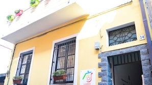 A building with multiple balconies, each with potted plants. There is a sign indicating a vacancy. - Case Vacanze Il Sorriso (Catania)