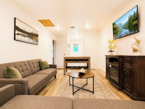 A living room with a sofa, a coffee table, a fireplace, and two paintings. - Spacious 3BR Family-Friendly, Big Yard, Game Table Near I-35 (Austin)