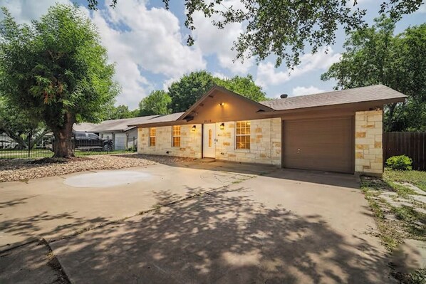 A single-story house with a garage, a driveway, and a tree in the foreground.