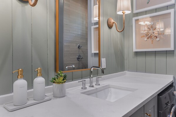Une salle de bain moderne dotée d’un grand miroir, de deux lavabos et d’un lave-linge encastré.