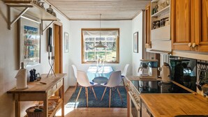 Una cucina compatta con zona pranzo, mobili in legno e vista dalla finestra.