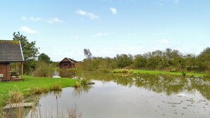 A rustic cabin with a pond in front, surrounded by greenery and trees. - A great location to explore the stunning East Riding of Yorkshire. (Fitling)