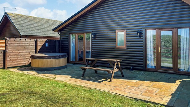 A log cabin with a hot tub, a picnic table, and a wooden deck. - A great location to explore the stunning East Riding of Yorkshire. (Fitling)