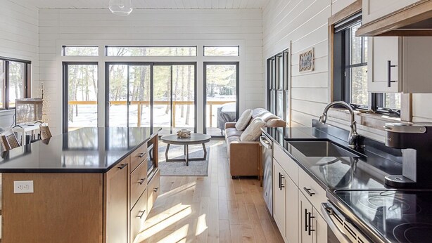 A modern kitchen with a large island, wooden cabinets, and a view of the outdoors. - Lakefront, brand new, craftsman style 4-bedroom 2 bath house home on Long Lake. (Bridgton)