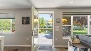 A modern interior with a door leading to an outdoor patio, a white console table, and a view of the garden.