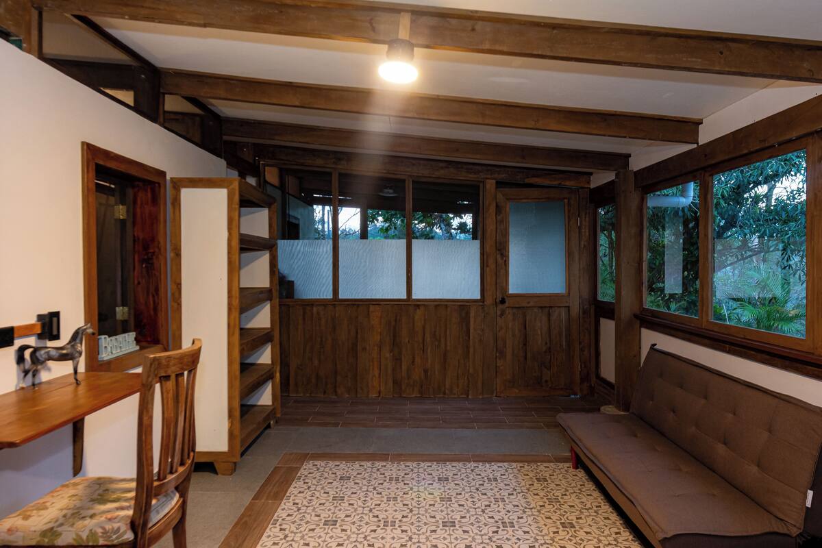 Una habitación con un banco de madera, una mesita y una escalera que sube a un balcón.