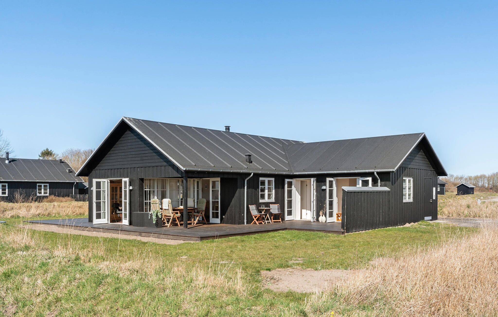 Ein modernes Haus mit zwei Etagen, einer großen Veranda, einem Essbereich und einer Garage.