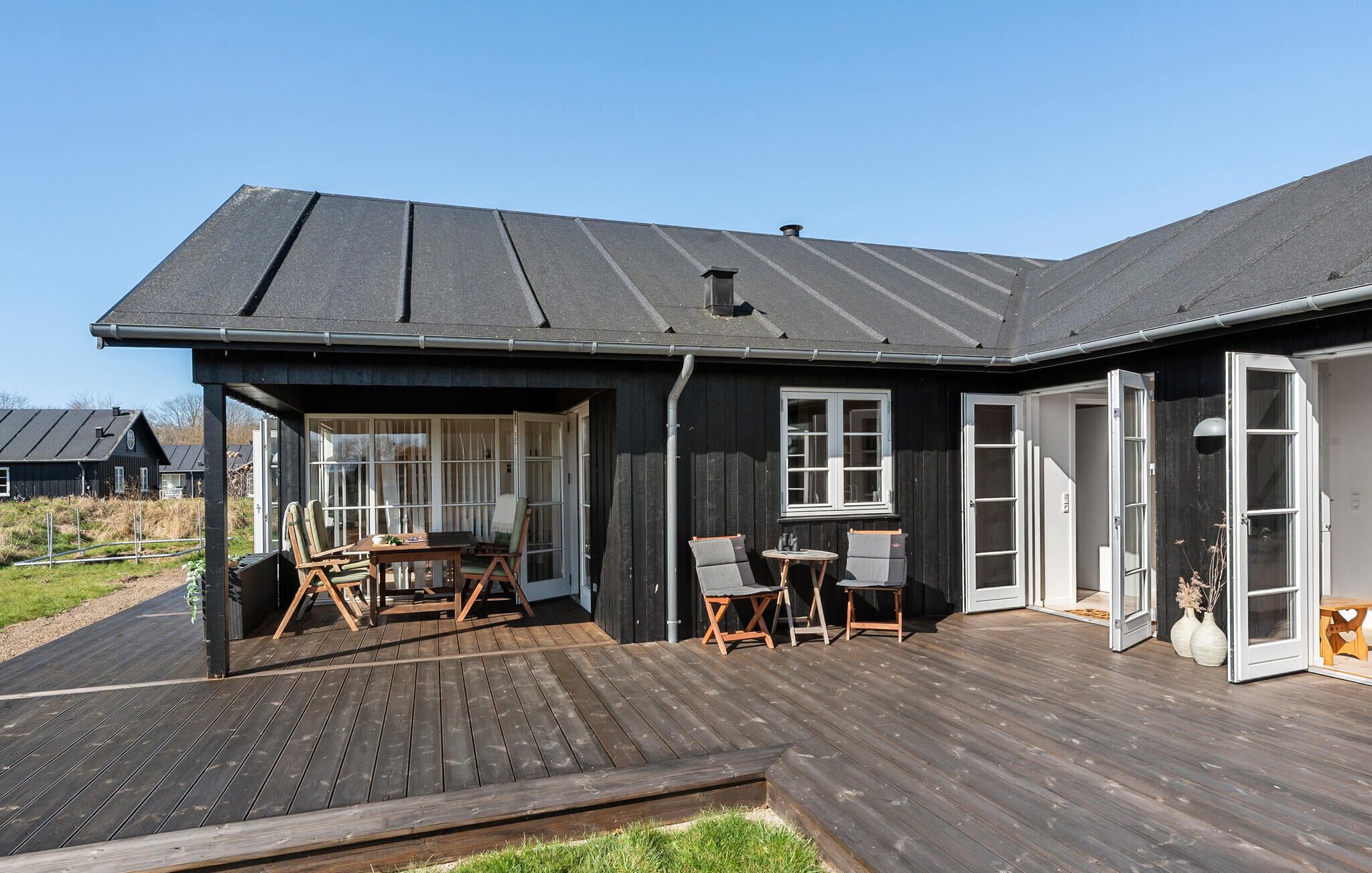 A modern house with a wooden deck, a covered patio, and a large window.