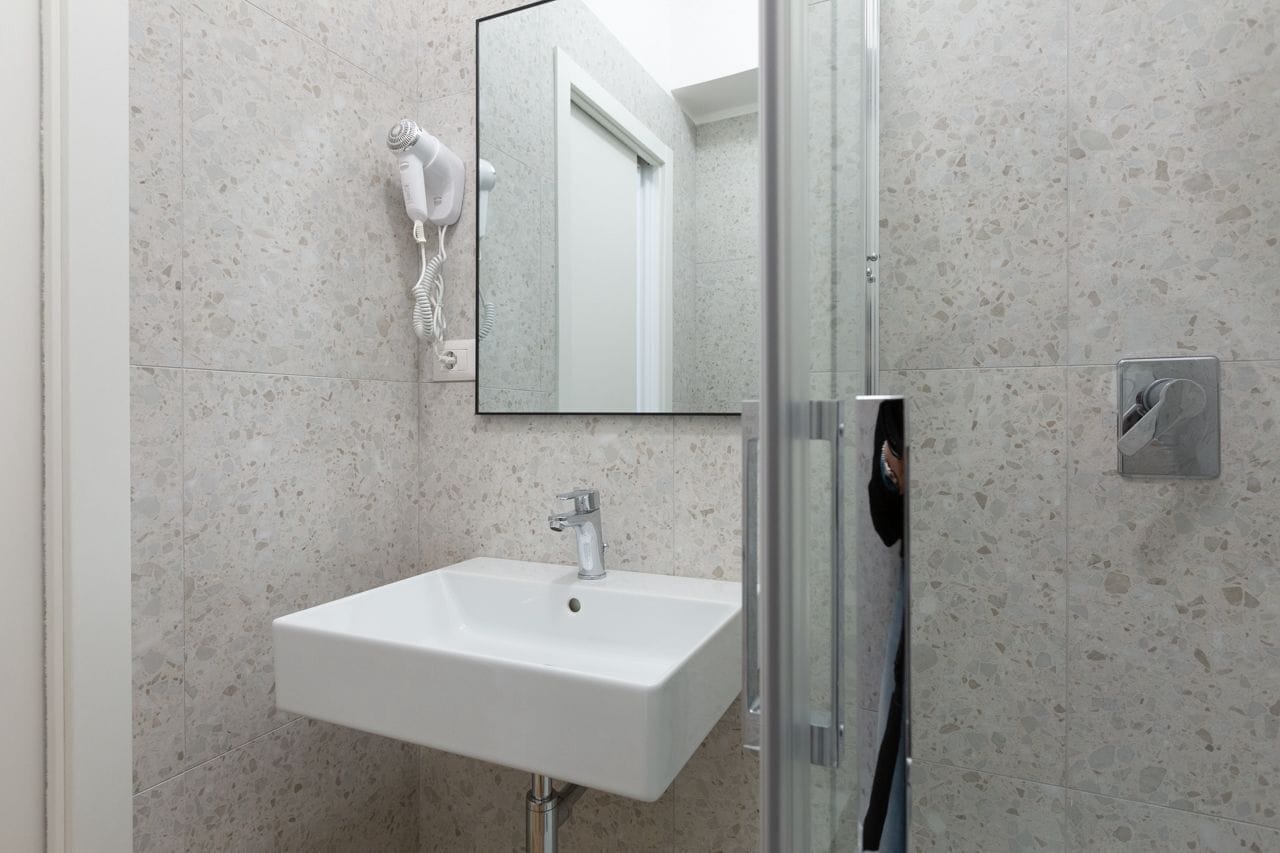 Een moderne badkamer met een wit wastafelmeubel, een douchecabine van glas en een spiegel.