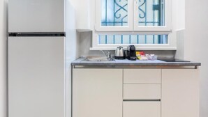 Una cuina amb nevera integrada, una finestra amb reixes metàl·liques, un rentaplatets i un búllet a la superfície de treball.