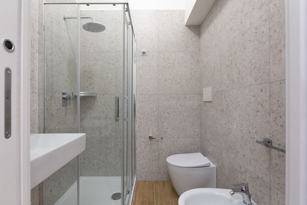 A modern bathroom with a glass-enclosed shower, a white toilet, and a sink.