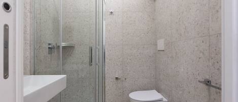 A modern bathroom with a glass-enclosed shower, a white toilet, and a sink.