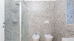 Un bany modern amb dutxa, bidet i vàter, amb parets de rajola petaca i terra de fusta.