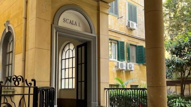Entrada d'un edifici amb un cartell que diu "SCALA 1" i un conjunt d'escales que hi condueixen.