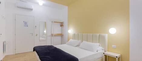 Una camera da letto con un letto, un comodino e uno specchio.