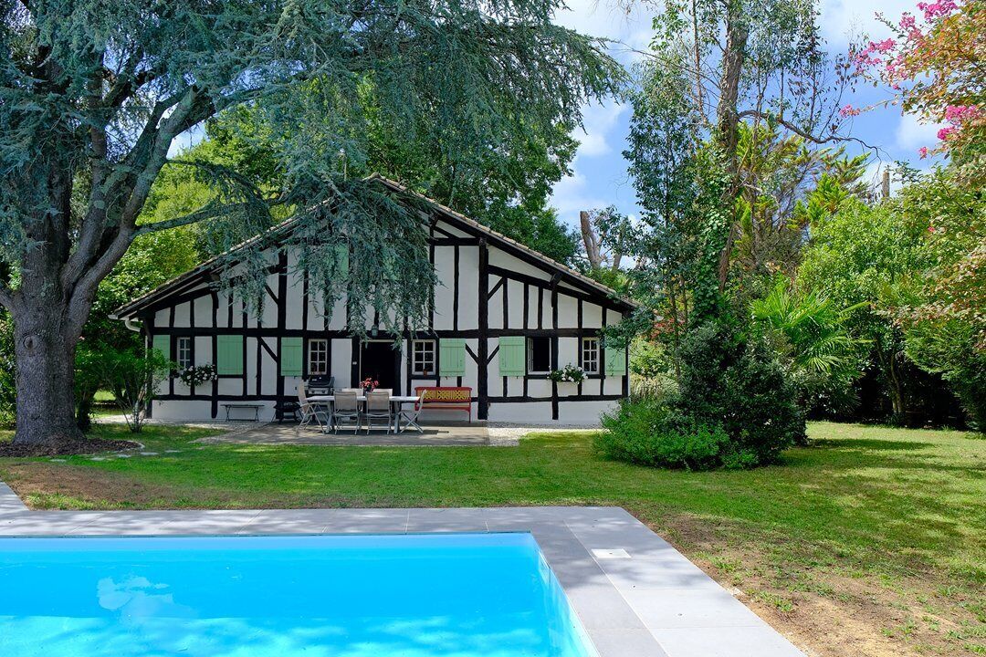 Una casa tradicional de entramado de madera con una piscina al frente.