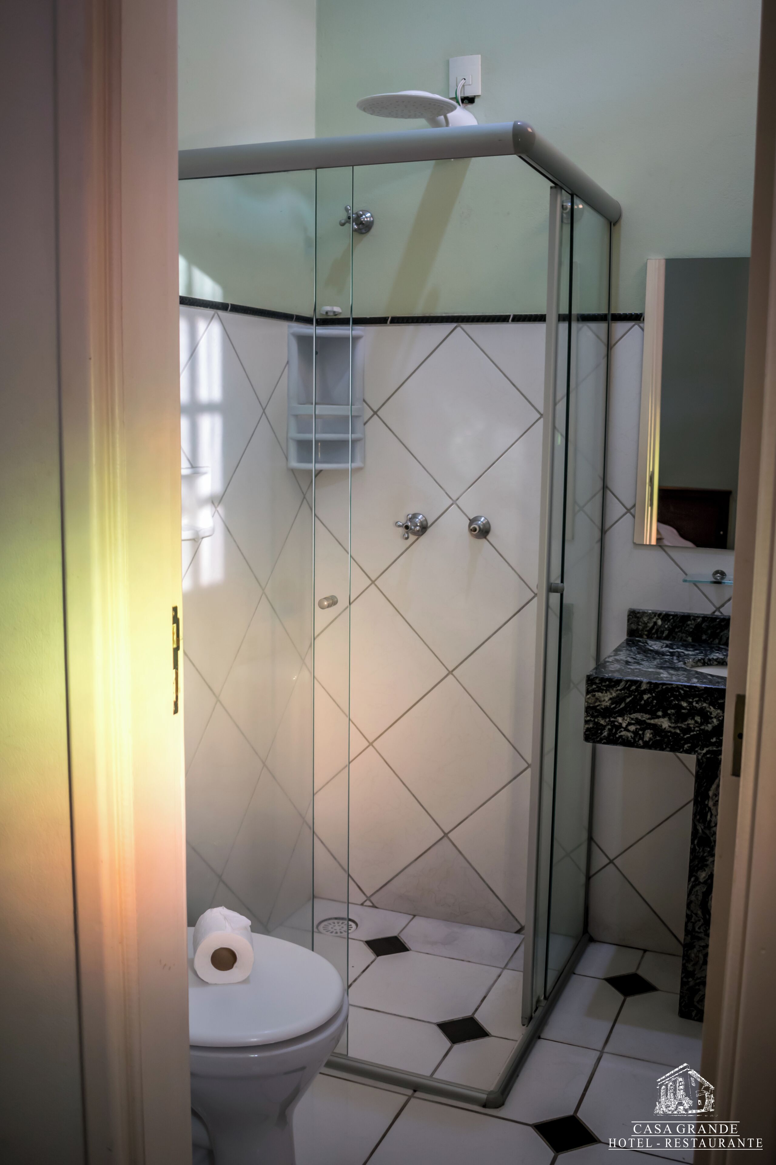 Un baño con cabina de ducha de vidrio, inodoro y lavabo con encimera de mármol.