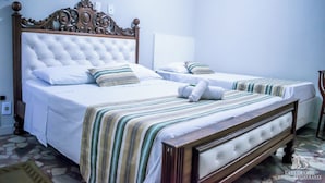 A hotel room with two beds, each with a striped bedspread and white linens.