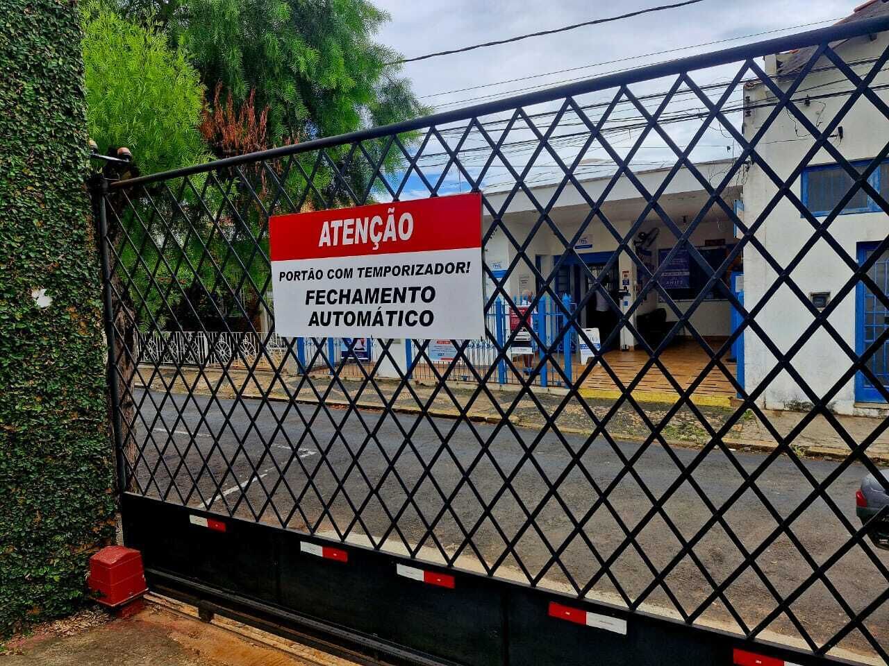 Entrada gradeada com placa indicando fechamento automático.