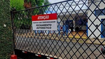 Entrada gradeada com placa indicando fechamento automático.