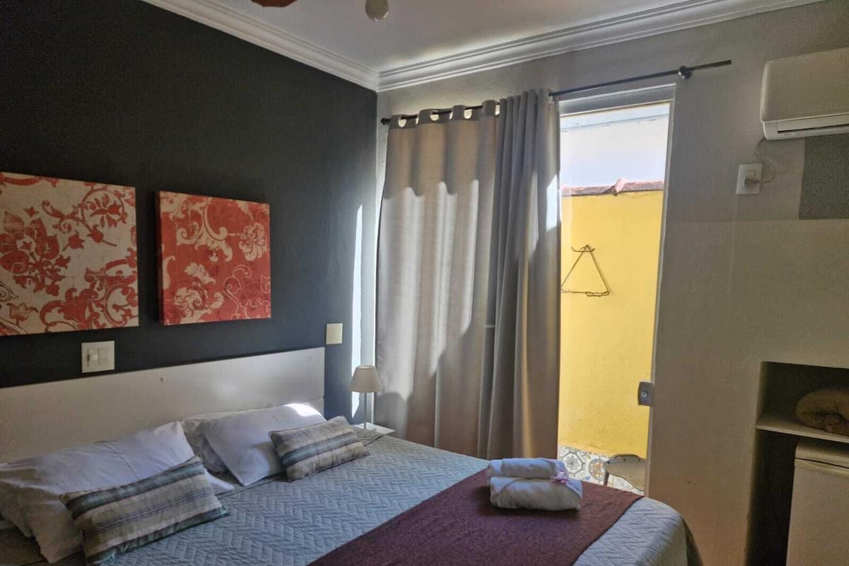 Ein Hotelzimmer mit Bett, einem Fenster mit Vorhängen und einer Wand mit zwei floralen Bildern.
