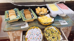 A buffet table with various food items including bread, pastries, and condiments.