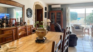 A spacious living room with a wooden dining table, a large mirror, and a stone archway. - Nice home in Montfrin (Montfrin)