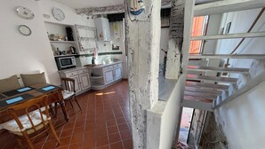 A kitchen with a microwave, stove, and sink. There is a dining table with chairs and a window with curtains. - House Old town 50m beach'shop (Menton)