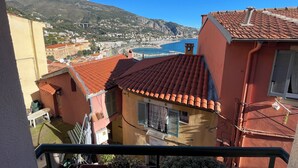 A balcony with a view of a coastal town, terracotta-roofed buildings, and a mountain in the background. - House Old town 50m beach'shop (Menton)