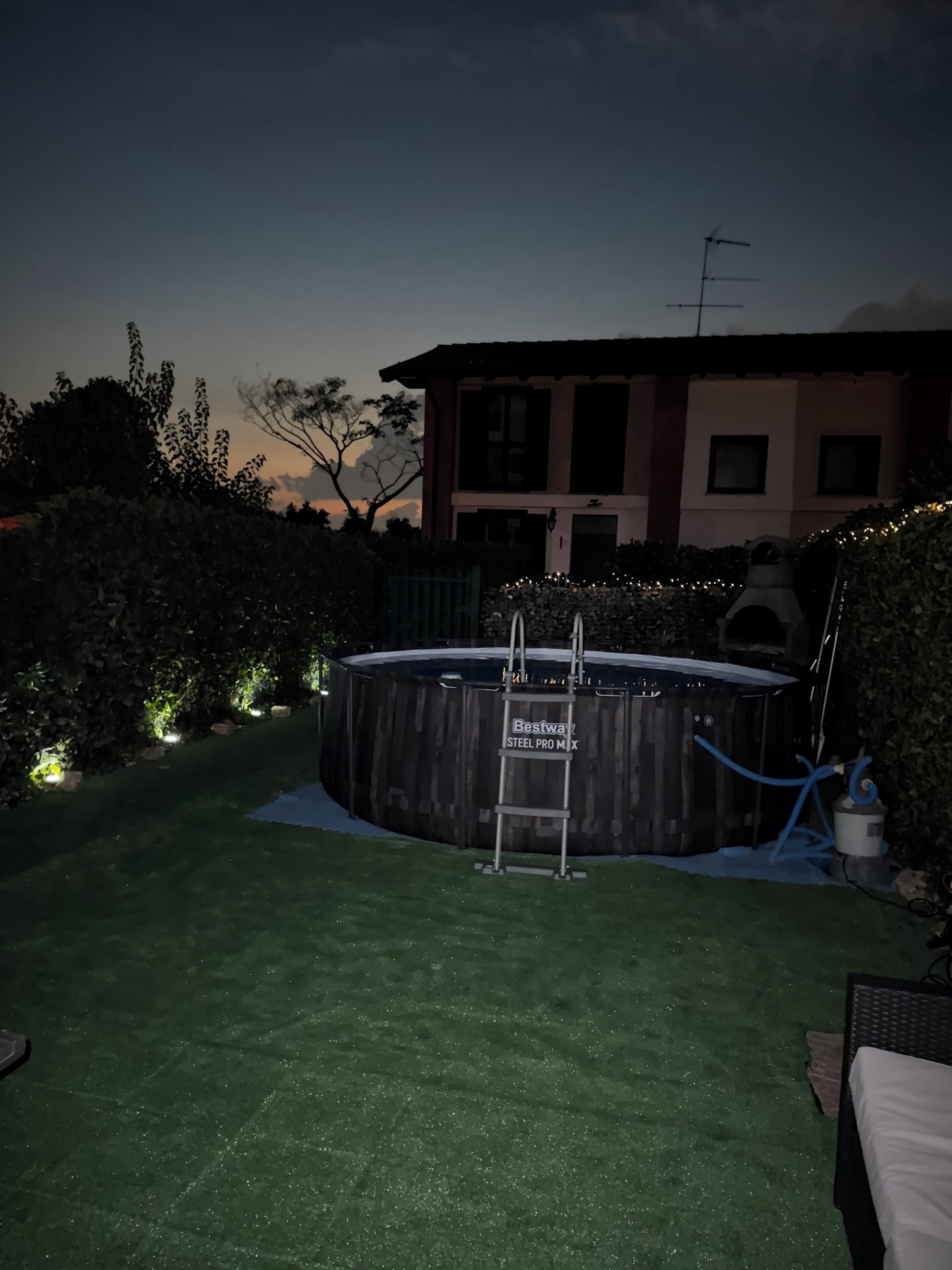 Un giardino con piscina, una scala e una casa sullo sfondo.