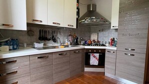 A modern kitchen with white cabinets, a gas stove, and a tiled floor.