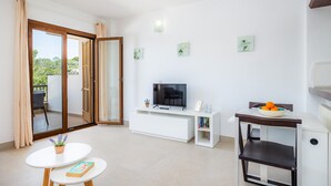 Ein modernes Wohnzimmer mit Fernseher, Esstisch, Stuhl und kleiner Bücherwand.