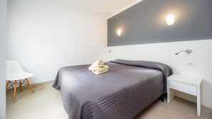 Ein modernes Schlafzimmer mit Bett, Nachttisch, Stuhl und Wandleuchte.