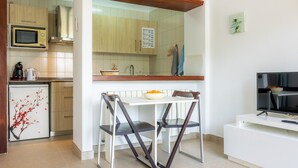 Una cocina compacta con microondas, refrigerador y comedor con sillas y una mesa.