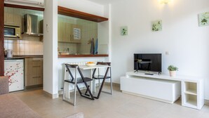 Una cocina moderna con comedor, televisor y una consola blanca.
