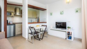 Un espace de vie compact comprenant un coin cuisine, un coin repas et un téléviseur posé sur un meuble.