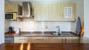 Une cuisine moderne avec des meubles en bois, une hotte en acier inoxydable, un four à micro-ondes, une machine à café et un évier.