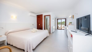 Habitación de hotel con cama, televisor, escritorio y vistas al exterior.