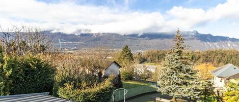 A residential area with houses, a grassy yard, and a mountain range in the background.