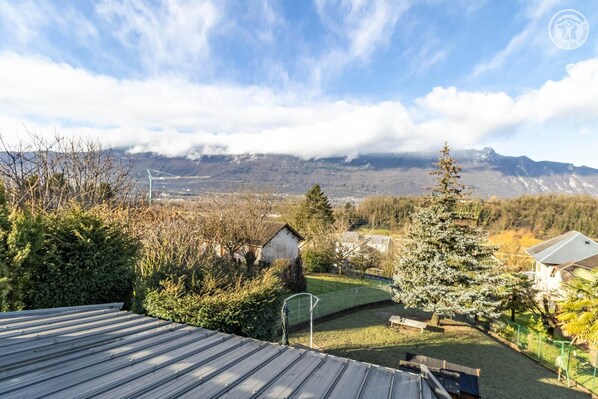 A residential area with houses, a grassy yard, and a mountain range in the background.