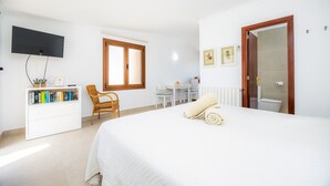 Une chambre à coucher comprenant un lit, un bureau, une chaise, un téléviseur et une bibliothèque.