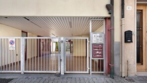 En indgang med låge, et skilt der forbyder parkering, en brandalarmanordning og en postkasse på højre side.