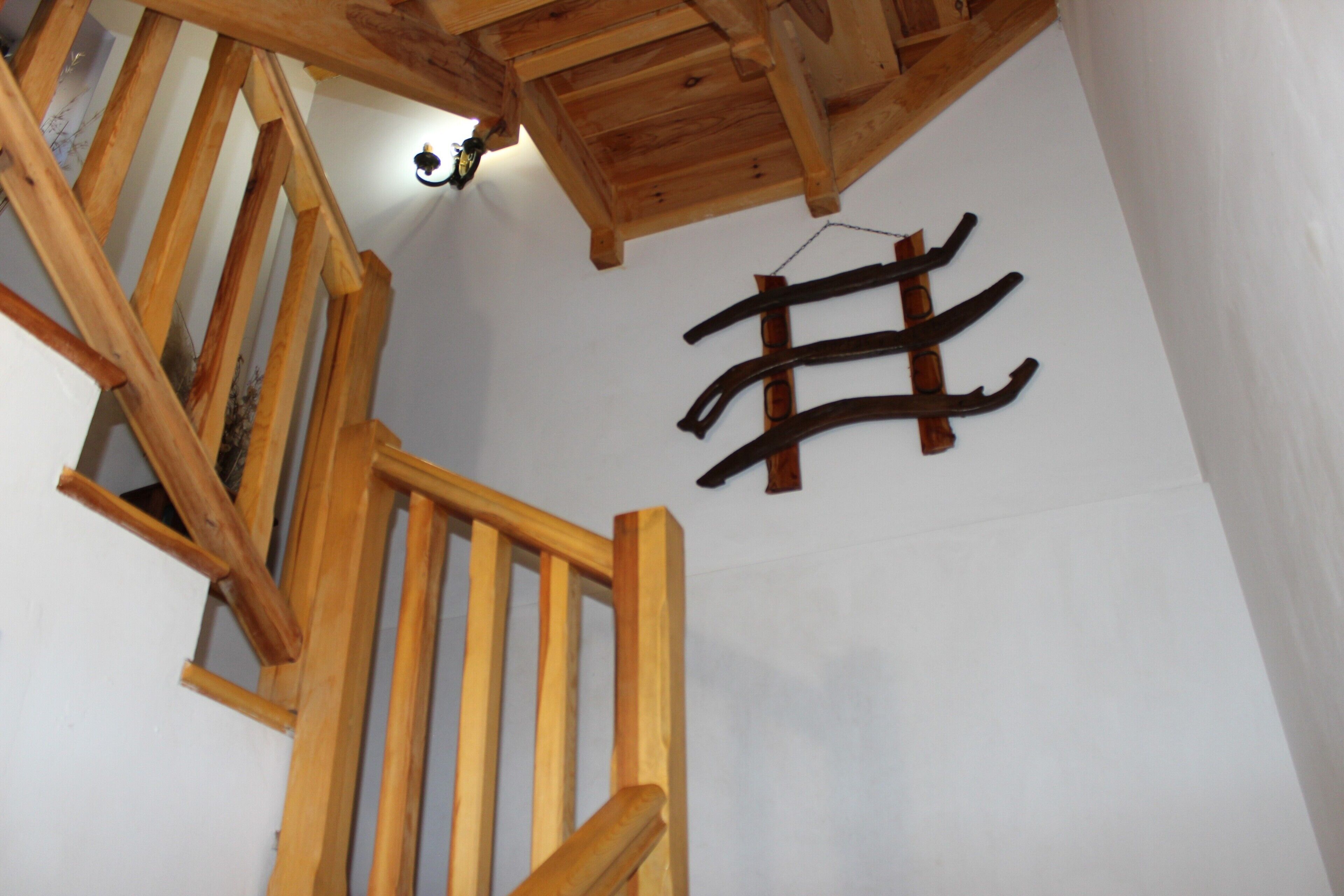Una escalera de madera con barandilla, techo de madera y perchero en la pared.