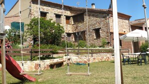A stone building with a swing set and a small bridge in the foreground.