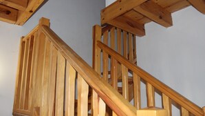 A wooden staircase with a handrail and wooden beams on the ceiling.