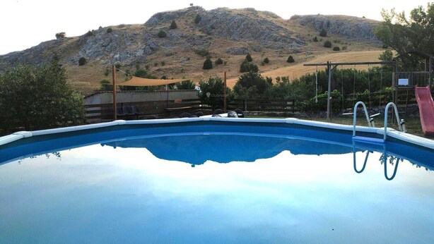 A swimming pool with a clear view of the surrounding landscape, including hills and trees.