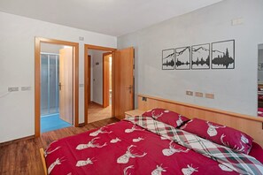Un dormitorio con una cama, cabecera de madera, una puerta y un cuadro con tres imágenes enmarcadas.
