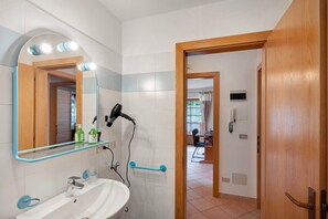 Un baño con lavamanos, espejo y secador de pelo.