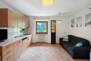 Una cucina moderna con mobili in legno, un divano nero e una finestra vista verde.