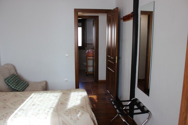 A bedroom with a bed, a chair, a wardrobe, and a mirror.